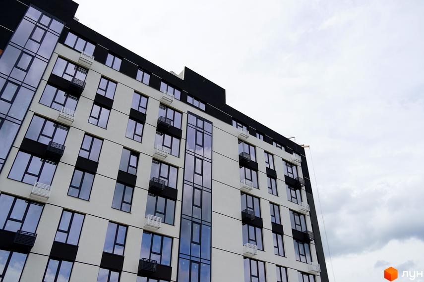 Фасад житлового комплексу SVIY з великою кількістю скління та балконами. Зовнішній вигляд новобудови з контрастними чорними та білими елементами.