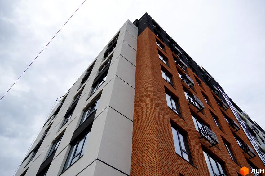 Зовнішній вигляд житлового комплексу SVIY з цегляним та білим фасадом, великою кількістю вікон та кондиціонерами на фасаді.