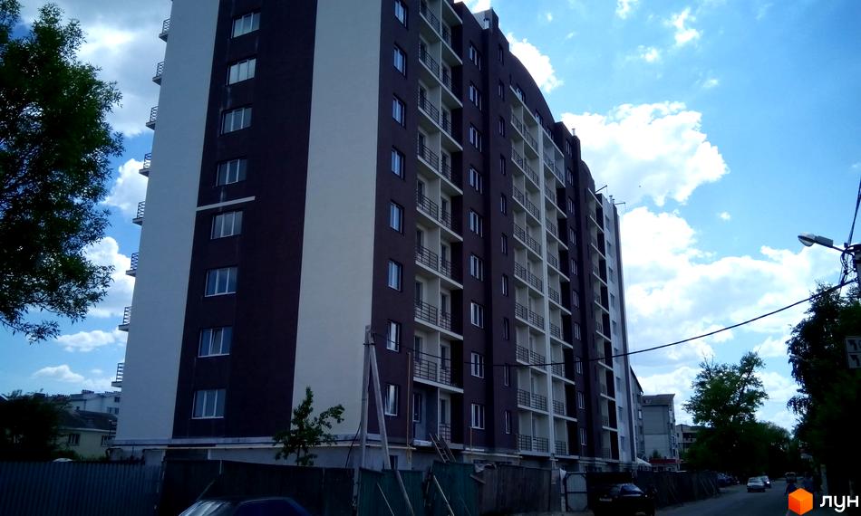 Зовнішній вигляд будинку ЖК Вишнева оселя на вул. Дружби. Багатоповерховий будинок з темним та білим фасадом, балконами та вікнами.