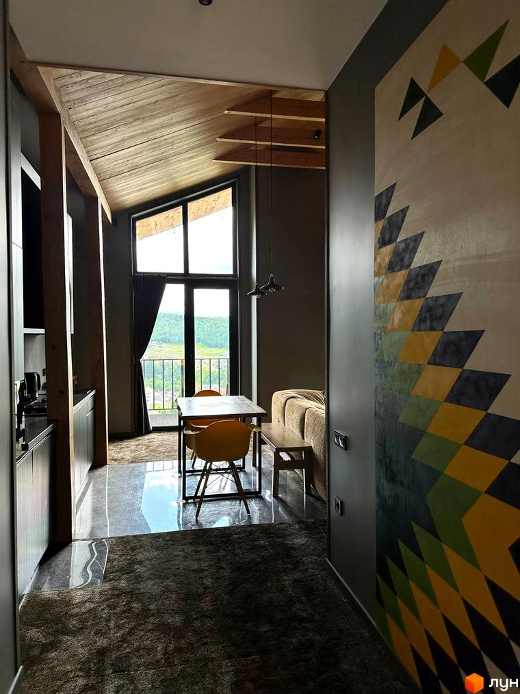 Апарт-готель Panorama Chalet. Сучасний інтер'єр з дерев'яними елементами та панорамним вікном з видом на зелені пагорби.