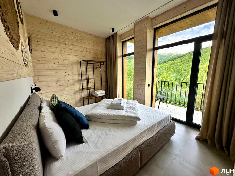 Апарт-готель Panorama Chalet. Затишна спальня з панорамним вікном та видом на зелені гори. Насолоджуйтесь краєвидами з балкона.
