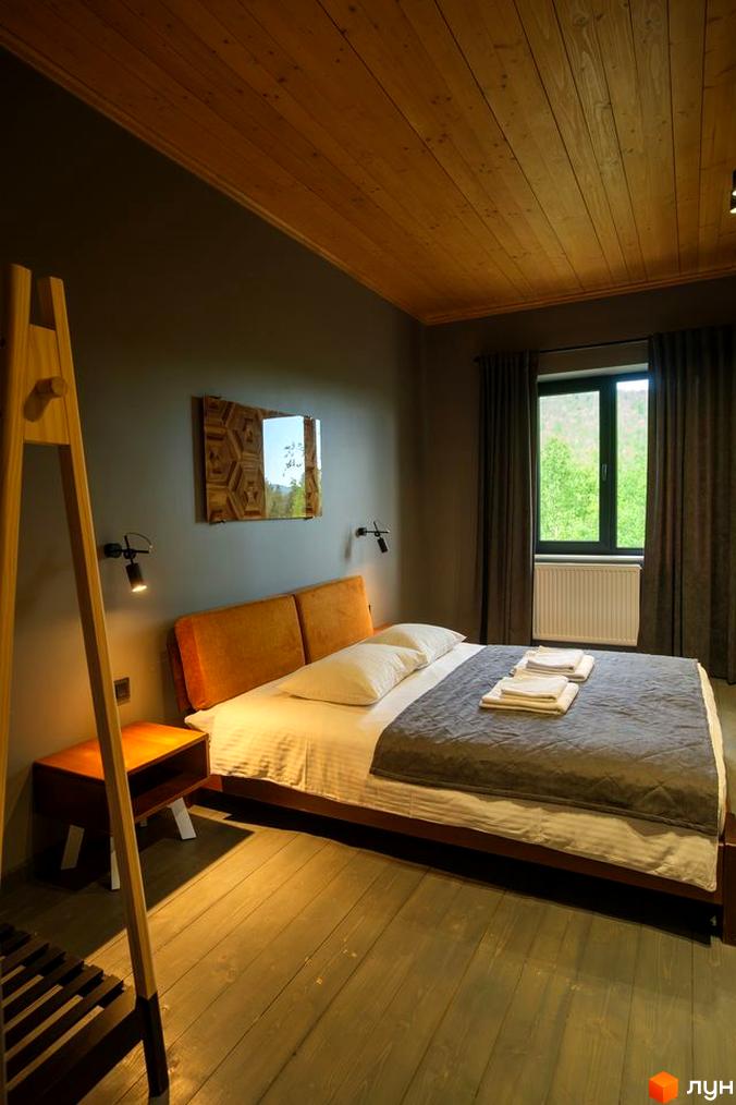 Затишна спальня в апарт-готелі Panorama Chalet з дерев'яною стелею та видом на зелені схили. Опис інтер'єру номера для бронювання.