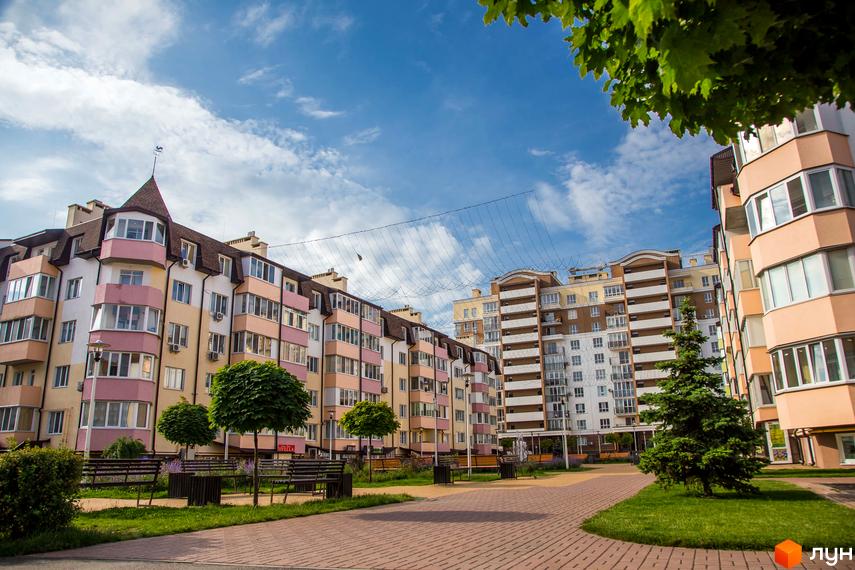 Житловий комплекс Піонерський квартал: фасади будівель з балконами та вікнами, зелена прибудинкова територія з лавками та деревами.