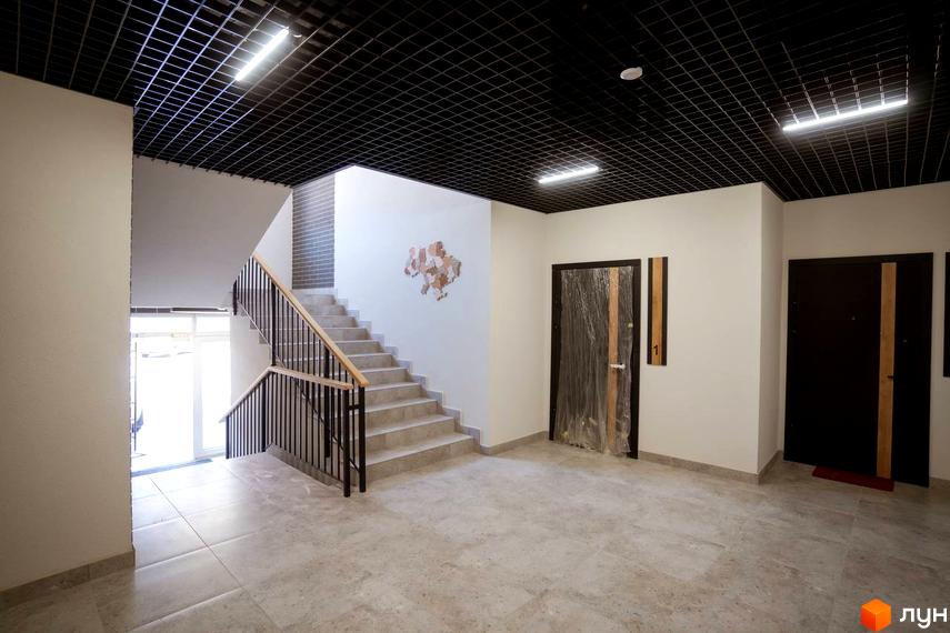 Вхідна група житлового комплексу Comfort House з мармуровими сходами та дверима. Оздоблення стін та стелі виконано в нейтральних тонах.