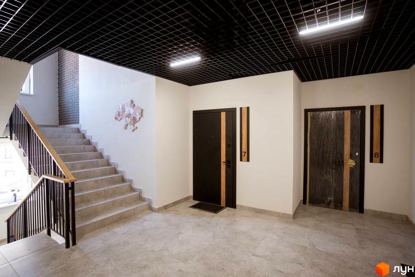 Вхідна група та сходова клітина в новобудові ЖК Comfort House. Сучасний дизайн інтер'єру з декоративними елементами на стінах.