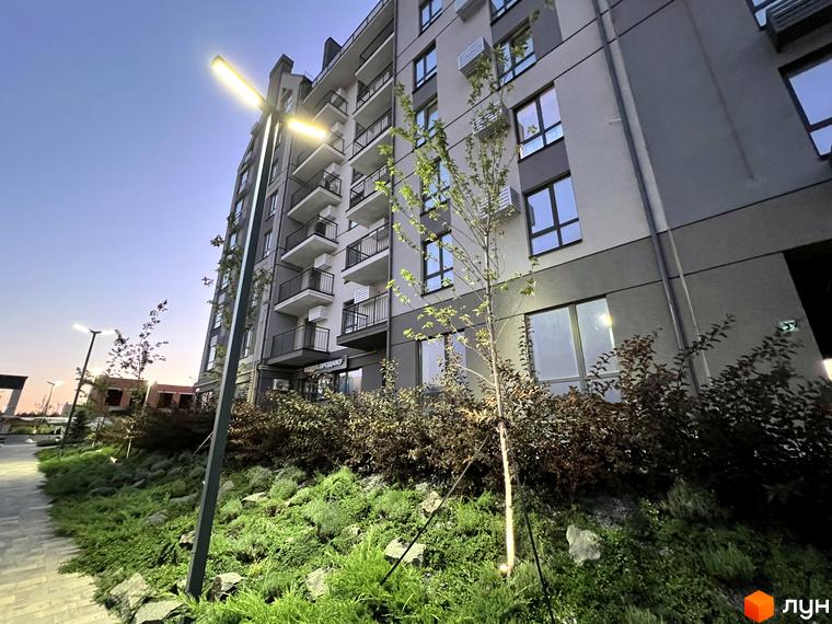 Житловий комплекс Park Residence з фасадом сірого та бежевого кольору, балконами та озелененою прибудинковою територією з деревами та кущами.
