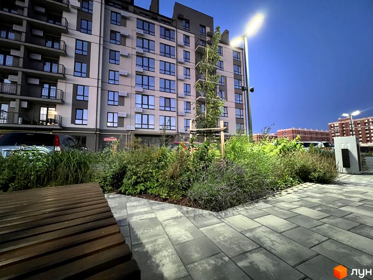 Житловий комплекс Park Residence: фасади будівель з великою кількістю вікон та балконів, зелена прибудинкова територія з лавкою та освітленням.