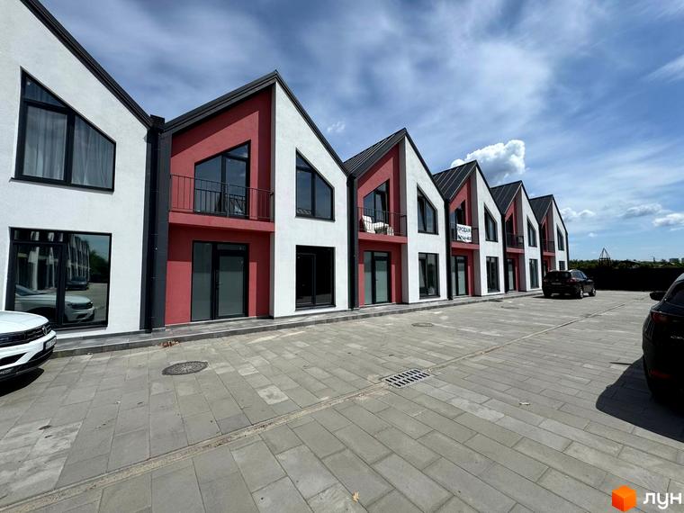 Таунхауси Freya – це двоповерхові будинки з червоними та білими фасадами, розташовані на бруківці з паркомісцями.