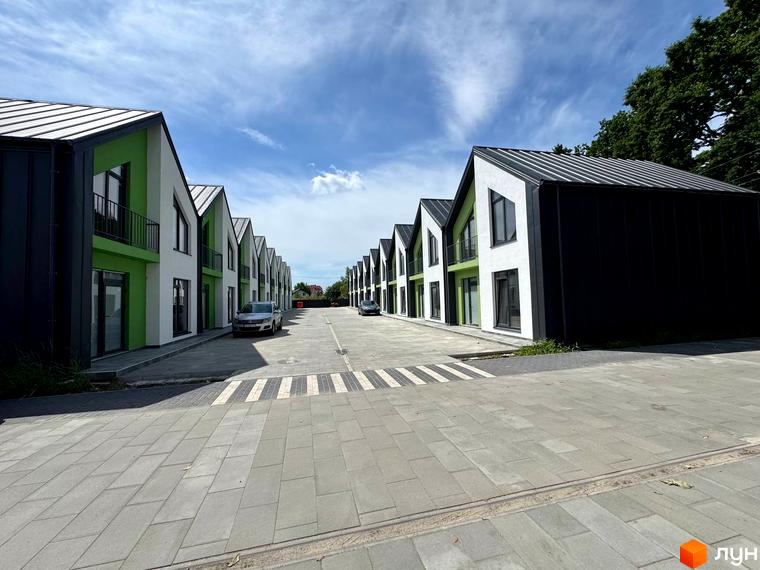 Таунхауси Freya – це ряд двоповерхових будинків з білими та зеленими фасадами, чорними дахами та прибудинковою територією з бруківки та паркуванням.