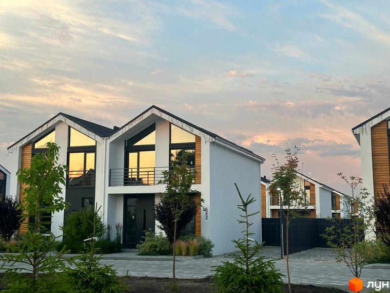 Котеджне містечко Gardd House Eco Village. Зовнішній вигляд будинків з великими вікнами та дерев'яними елементами, прибудинкова територія з зеленими насадженнями.