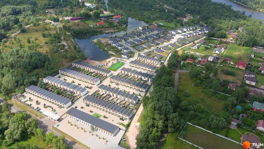Котеджне містечко КМ Prydesennya Eco Village з сучасними будинками та доглянутою прибудинковою територією біля озера. Оглядова аерофотозйомка житлового комплексу.