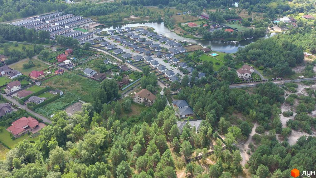 Котеджне містечко Prydesennya Eco Village з сучасними будинками та доглянутими прибудинковими територіями, розташоване біля озера та лісу.