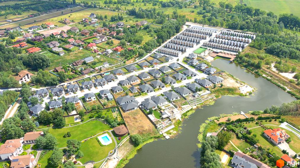 Котеджне містечко Prydesennya Eco Village з сучасними будинками та доглянутою прибудинковою територією біля озера.