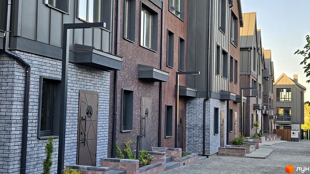 Фасад таунхаусів New Smart 17 з цегляним оздобленням та металевими елементами. Прибудинкова територія з бруківкою та зеленими насадженнями.