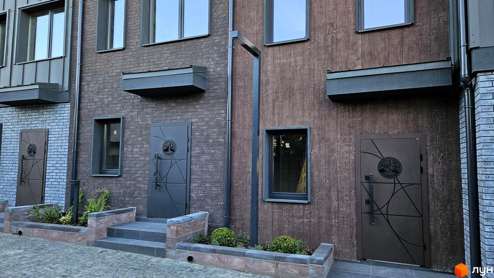 Таунхауси New Smart 17: фасади з цегли та дерев'яних панелей, вхідні групи з декоративними дверима та сходами.