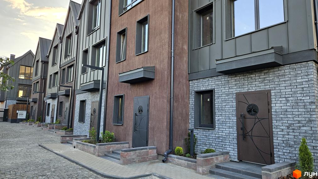 Таунхауси New Smart 17 з цегляним фасадом та дерев'яними елементами, розташовані на бруківці.