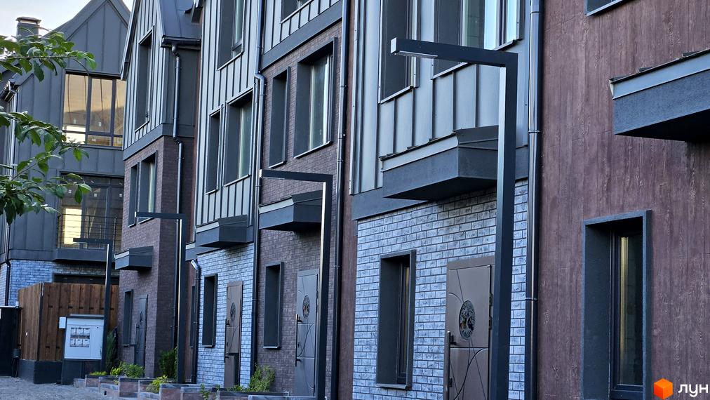 Зовнішній вигляд таунхаусів New Smart 17 з цегляним фасадом та дерев'яними елементами. Поруч розташована прибудинкова територія з освітленням.