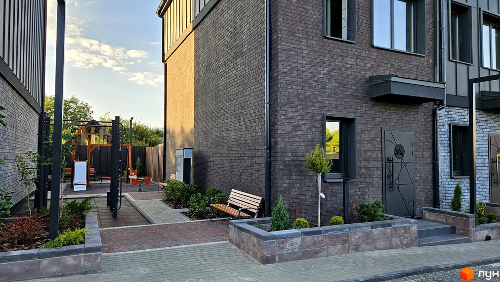 Таунхауси New Smart 17: фасади з темної цегли, вікна, двері та прибудинкова територія з дитячим майданчиком та лавками.
