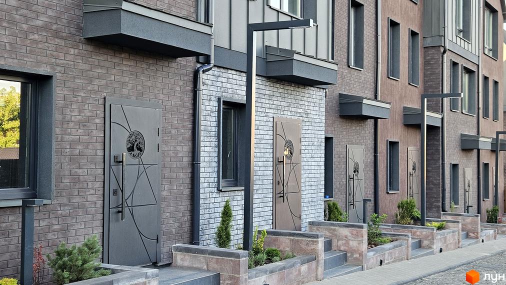 Таунхауси New Smart 17. Зовнішній вигляд будинків з цегляним фасадом та індивідуальними входами, прибудинкова територія з озелененням.