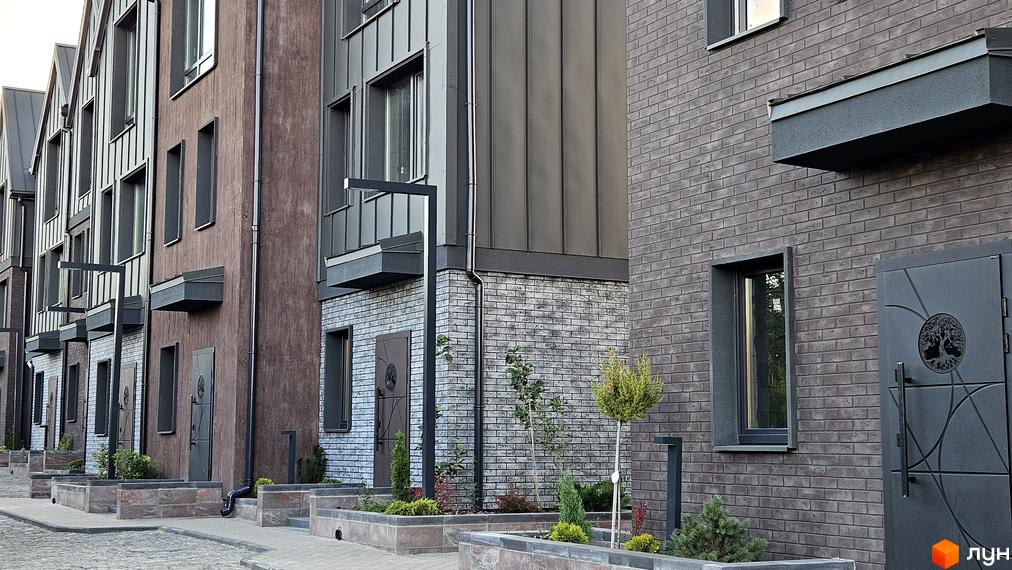 Зовнішній вигляд таунхаусів New Smart 17 з цегляним фасадом та металевими елементами. Прибудинкова територія з ландшафтним дизайном та бруківкою.