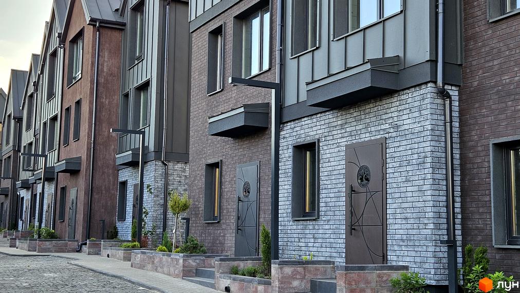 Фасад таунхаусів New Smart 17 з цегляним оздобленням та сучасними вікнами. Прибудинкова територія з бруківкою та зеленими насадженнями.