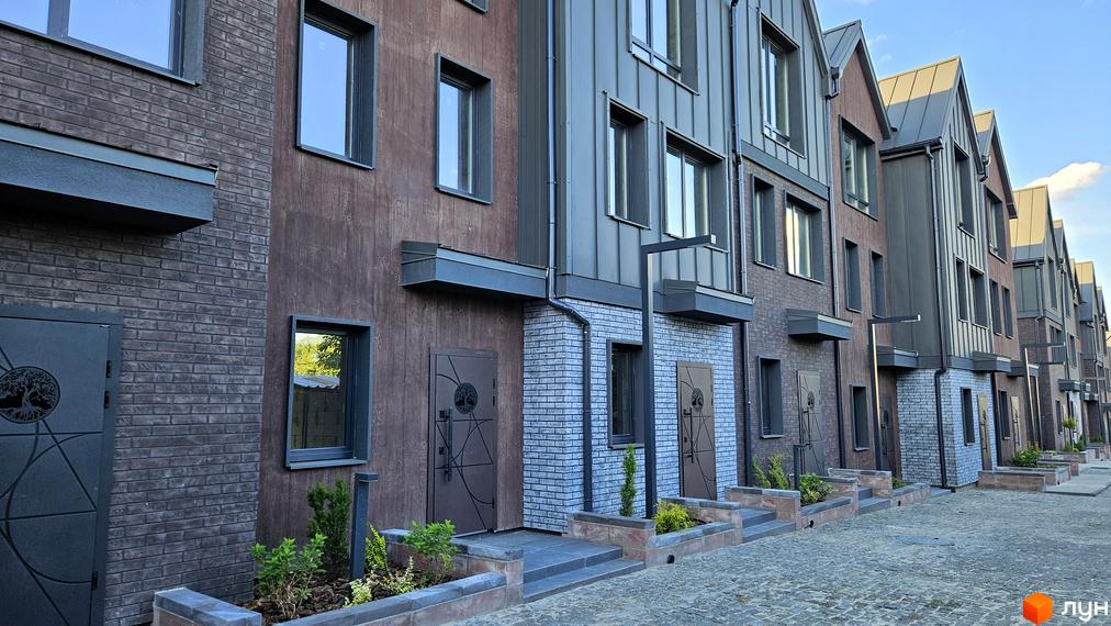 Таунхауси New Smart 17. Зовнішній вигляд будинків з цегляним та дерев'яним фасадом, металевими дахами та доглянутою прибудинковою територією з рослинами.