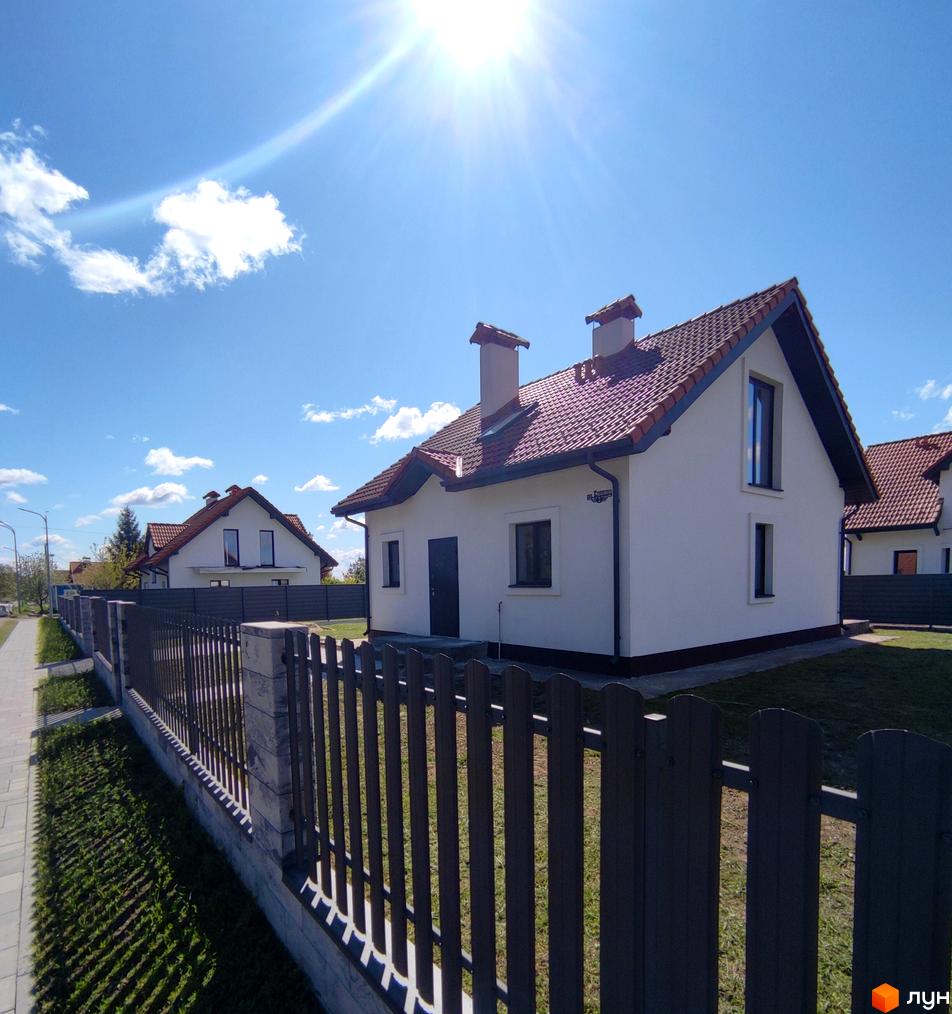 Котеджне містечко КМ Ivankovo: білі будинки з червоними черепичними дахами та парканом. Прибудинкова територія з газоном та тротуаром.