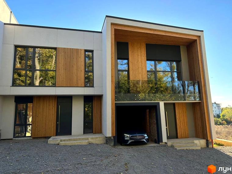 Таунхауси FIRST – це двоповерхові будинки з дерев'яними та сірими фасадами, великими вікнами та балконами. Перед будинком розташований навіс для автомобіля та гравійна доріжка.