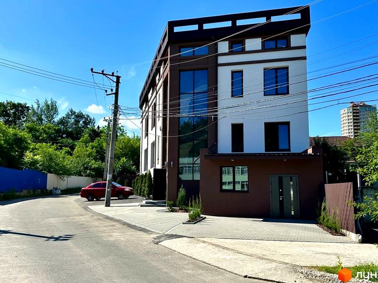 Житловий комплекс Olympia house – це сучасна новобудова з великими вікнами та коричневими елементами фасаду. Перед будинком розташований доглянутий двір з бруківкою та зеленими насадженнями.