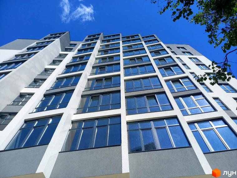 Фасад житлового комплексу Argo з великою кількістю скління. Будинок має сучасну архітектуру з білими та сірими елементами.