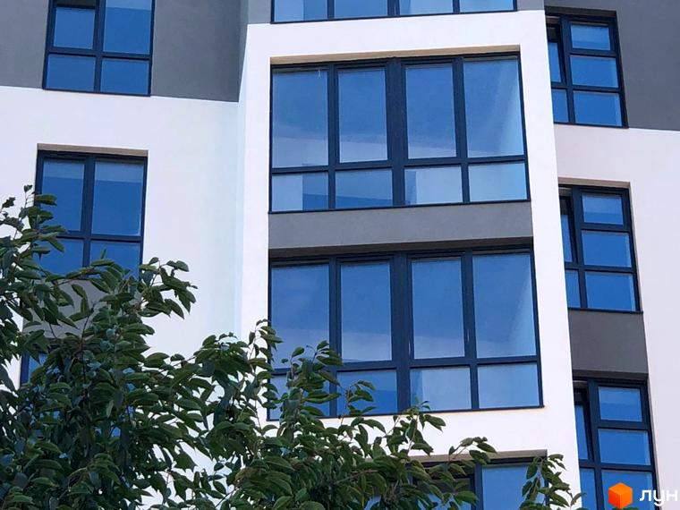 Зовнішній вигляд новобудови ЖК Argo з великими вікнами та зеленою зоною попереду. Комплекс Argo має сучасний дизайн фасаду.