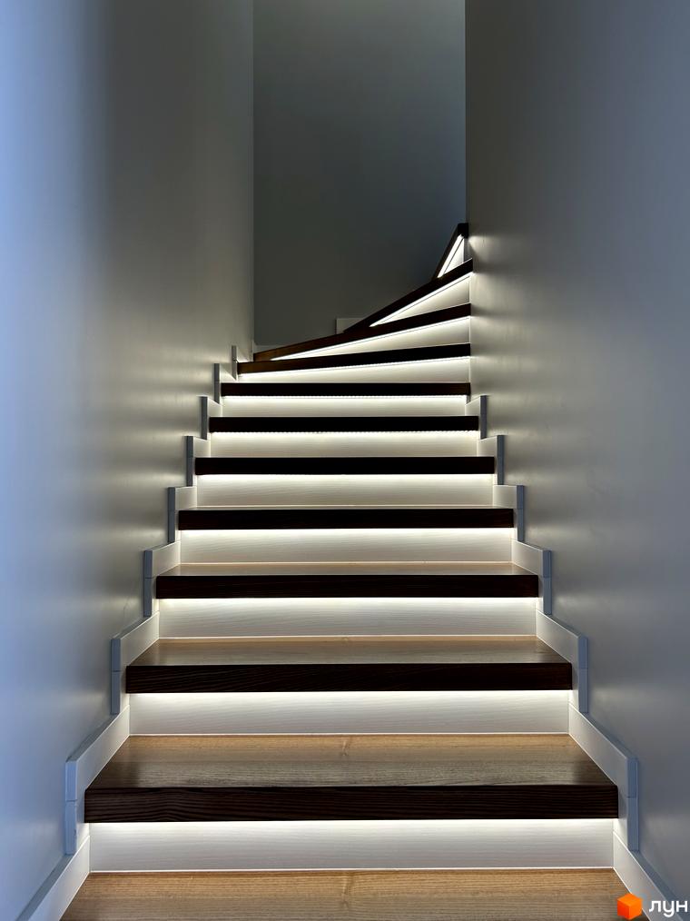 Світлі сходи з дерев'яними елементами та підсвіткою в Peremohy Homes. Сучасний дизайн сходів, що підкреслює елегантність інтер'єру.