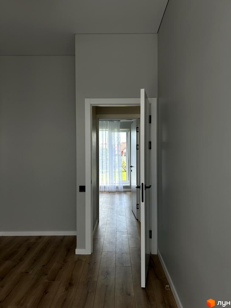 Peremohy Homes: двері відчинені, веде до кімнати з білими шторами та вікном, за яким видно зелень та будинки.