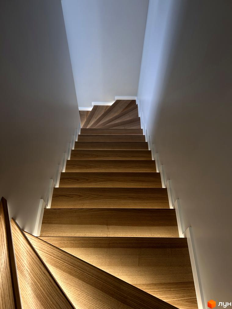 Сучасні дерев'яні сходи з підсвіткою в житловому комплексі Peremohy Homes. Елегантний дизайн сходів підкреслює стиль новобудови.