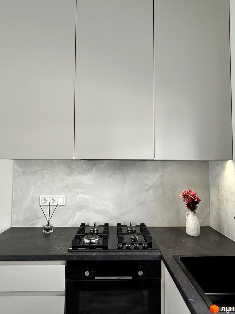 Сучасна кухня з газовою плитою та раковиною. Кухонні шафи світло-сірого кольору.