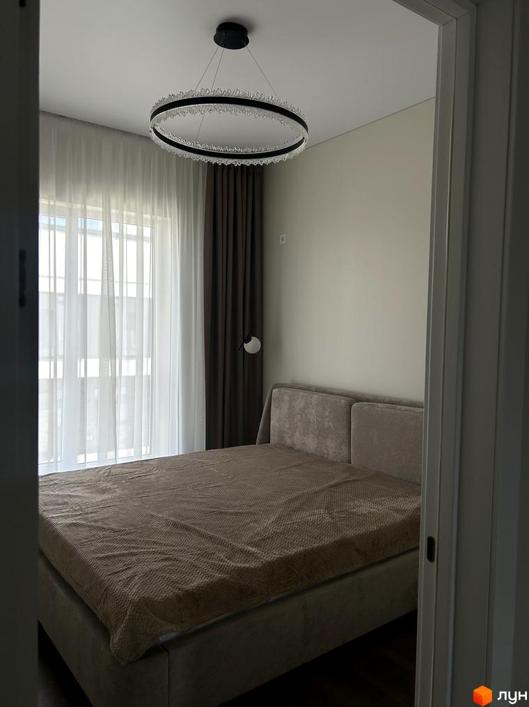 Затишна спальня в таунхаусі Peremohy Homes з великим вікном та елегантною люстрою. Комплекс пропонує комфортне проживання.