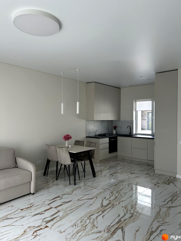 Дизайн інтер'єру кухні-вітальні в Peremohy Homes з обіднім столом та диваном. Сучасні меблі та оздоблення створюють затишну атмосферу.