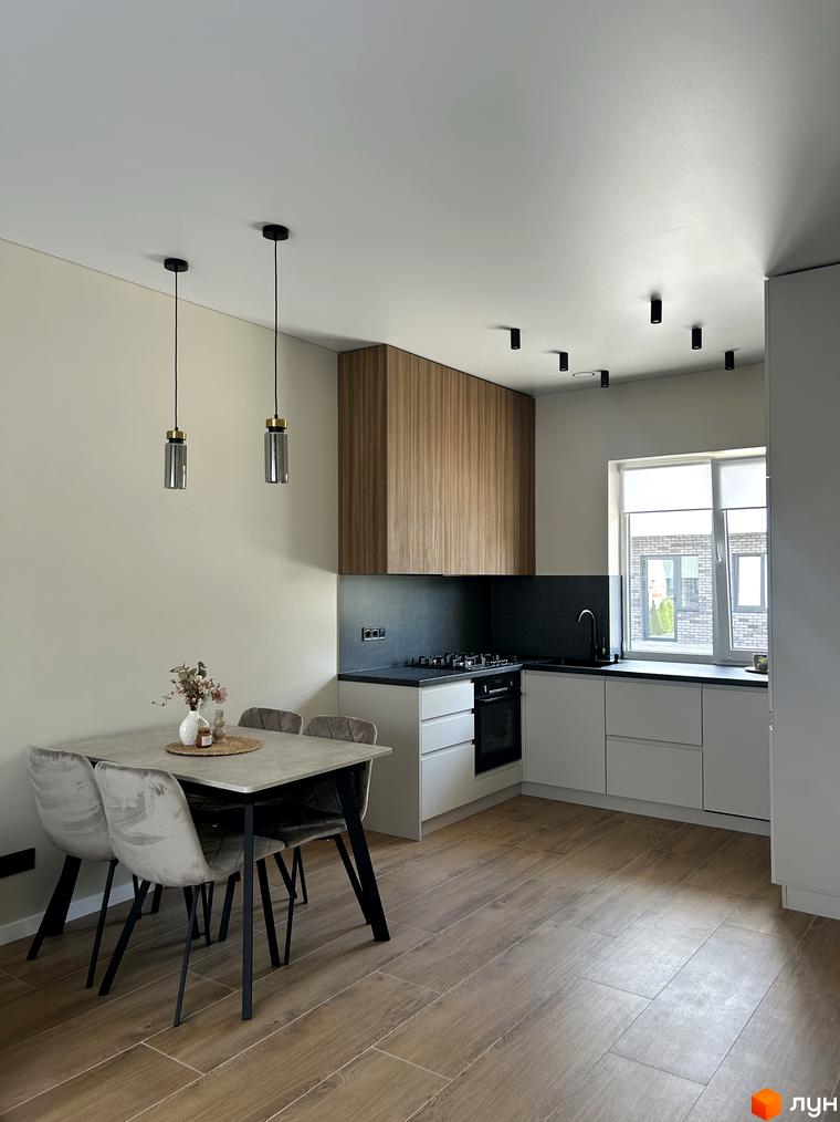 Кухня-вітальня в Peremohy Homes з обіднім столом та стільцями, сучасними світильниками та кухонним гарнітуром.