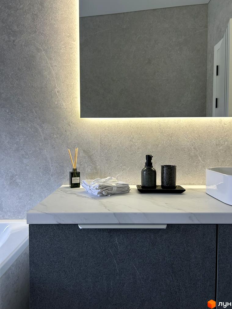 Сучасний дизайн ванної кімнати з сірою плиткою та мармуровою стільницею. На стільниці стоять аксесуари для ванної кімнати.