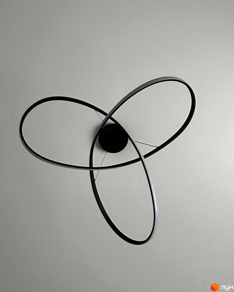 Сучасний дизайн світильника з трьома чорними кільцями, що переплітаються, на фоні світлої стелі. Деталі освітлення для Peremohy Homes.