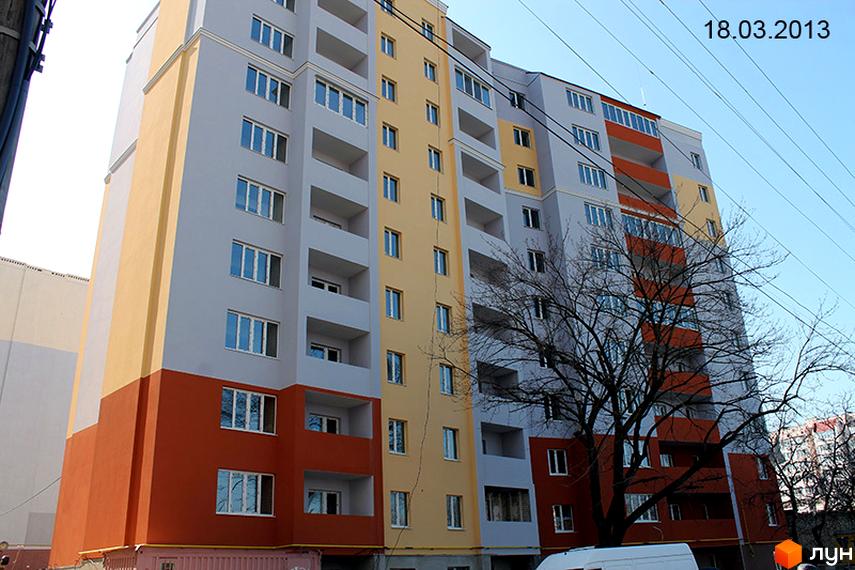 Багатоповерховий житловий будинок за адресою вул. Ковалевського (Пішонівська), 37, з секціями світло-сірого, жовтого та теракотового кольорів. Навколо будинку росте дерево без листя.