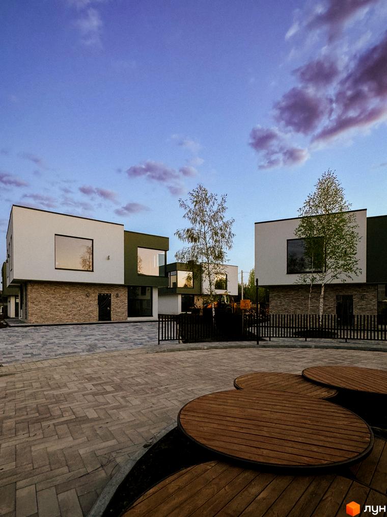 Котеджне містечко Barcelona. Зовнішній вигляд будинків з великими вікнами та цегляною основою. Прибудинкова територія з дерев'яними елементами та бруківкою.