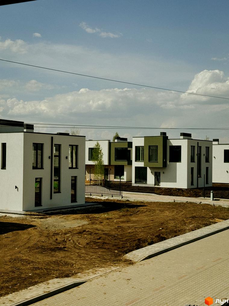 Котеджне містечко Barcelona: білосніжні будинки з темними вікнами та зеленими акцентами, огороджена територія з доглянутим ландшафтом.