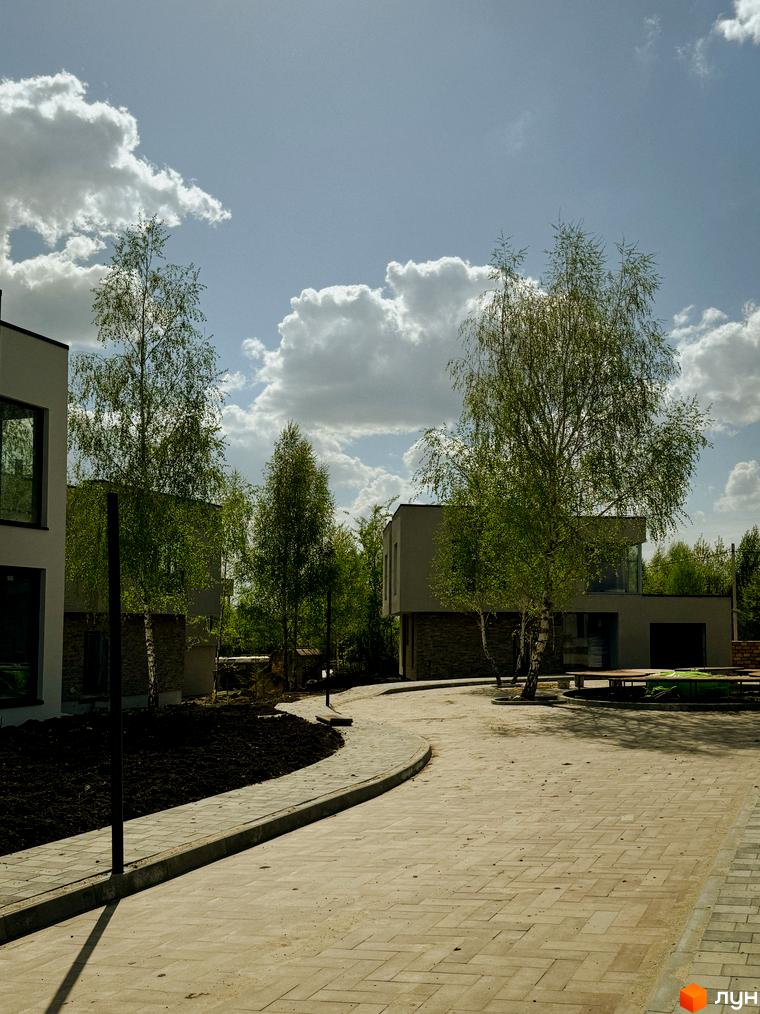 Котеджне містечко Barcelona: двоповерхові будинки з великими вікнами та цегляним цоколем, оточені деревами та вимощеною доріжкою.