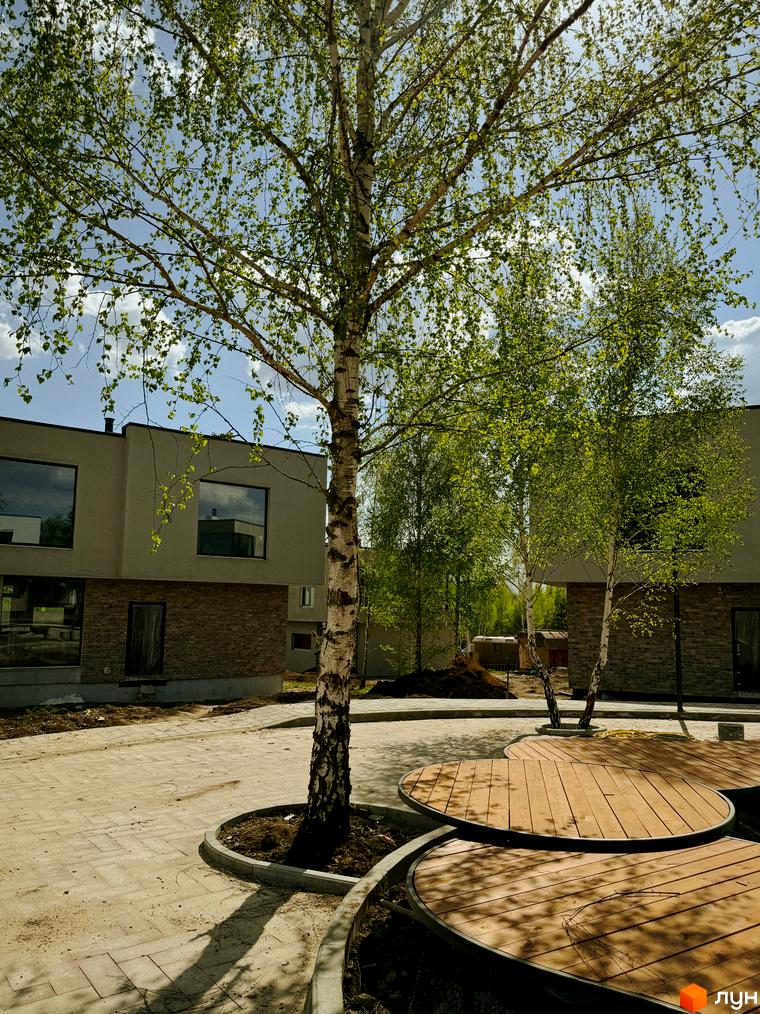 Котеджне містечко Barcelona: двоповерхові будинки з великими вікнами та цегляною обробкою, оточені зеленню та дерев'яними зонами відпочинку.