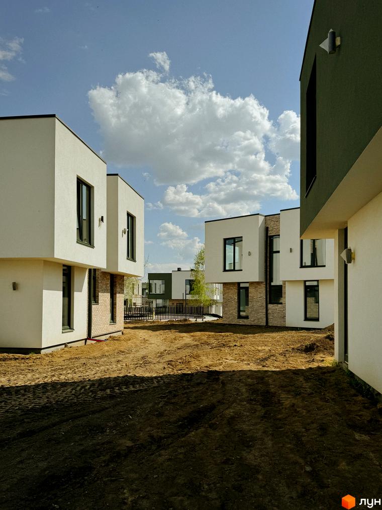 Котеджне містечко Barcelona: білі та зелені будинки з темними вікнами, цегляні вставки, будмайданчик з піском та травою.