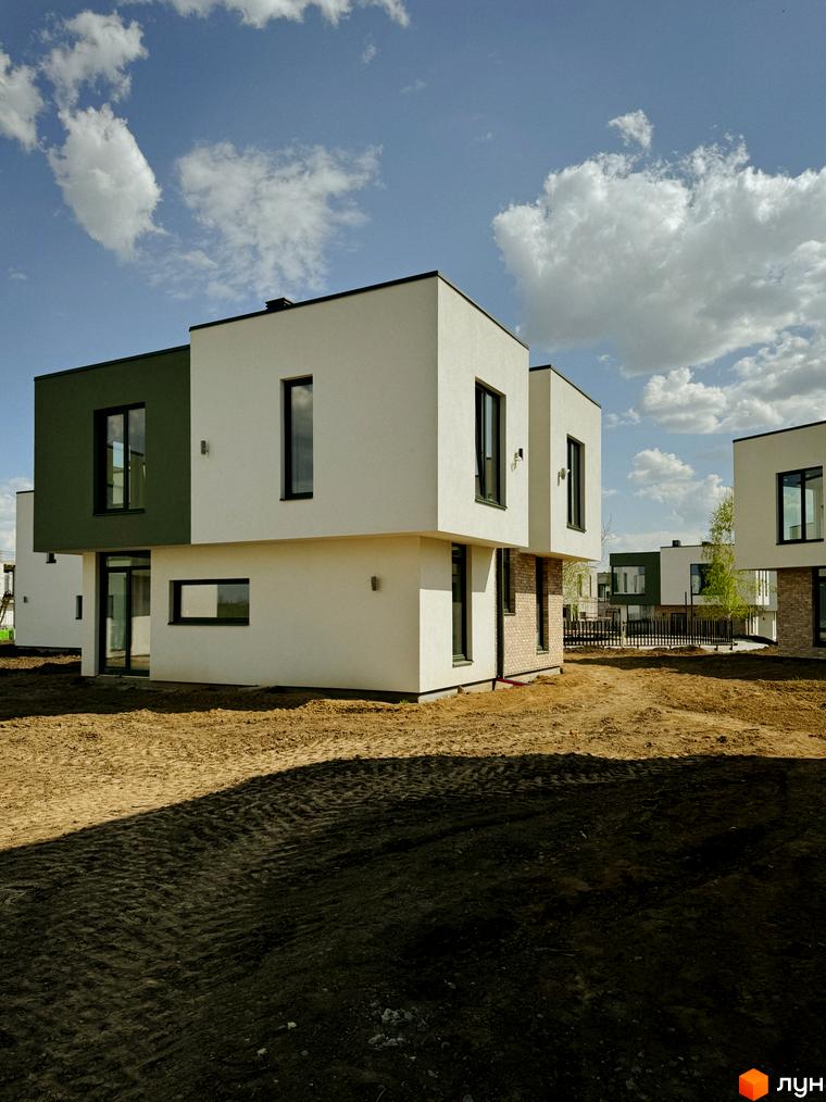 Котеджне містечко Barcelona: двоповерхові будинки з білими та зеленими фасадами, великими вікнами, на тлі блакитного неба з хмарами. Територія навколо будинків вкрита землею.