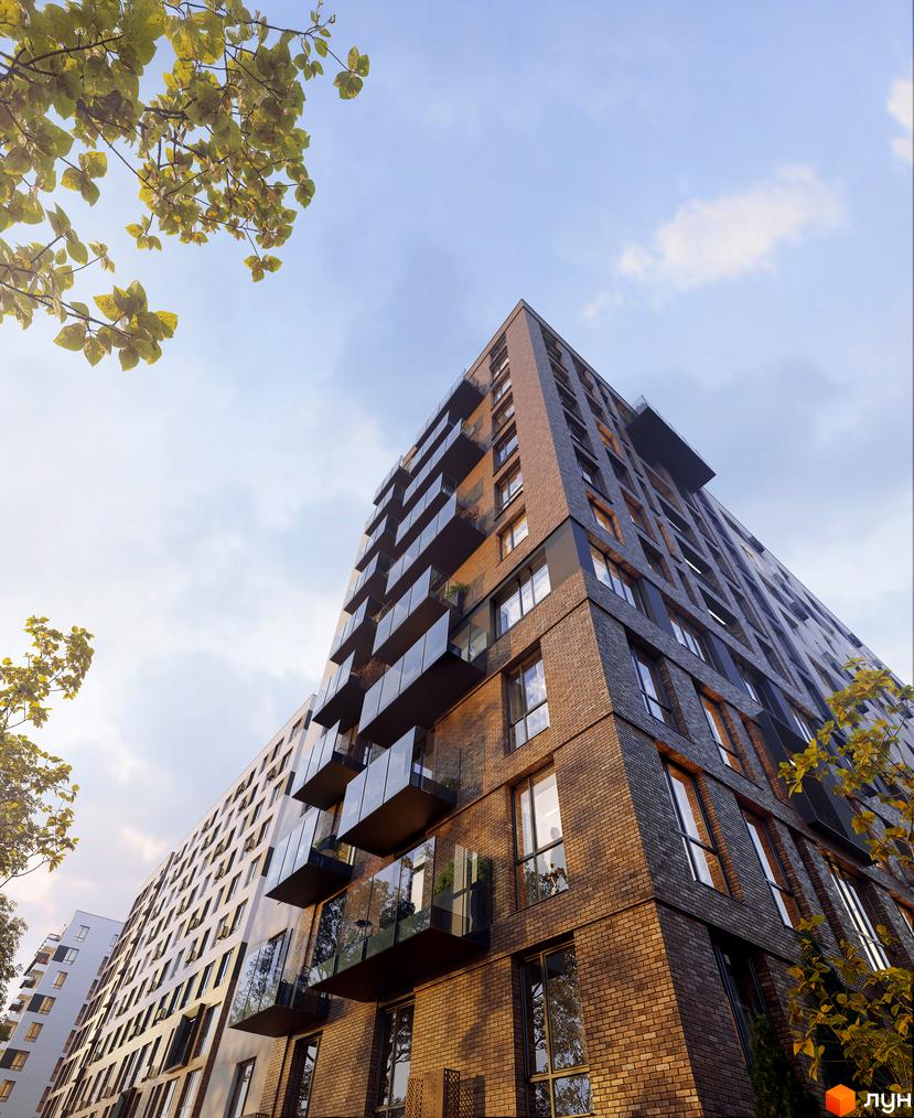 Будинок житлового комплексу Premier Bay з цегляним фасадом та скляними балконами на фоні блакитного неба з деревами. Зовнішній вигляд новобудови.