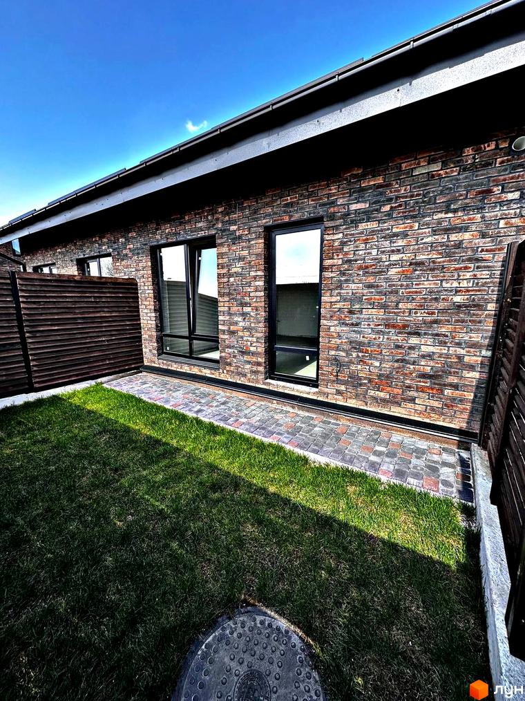 Одноповерховий Київ - Малехів: фасади з цегли та вікна, зелена галявина та доріжка з бруківки.