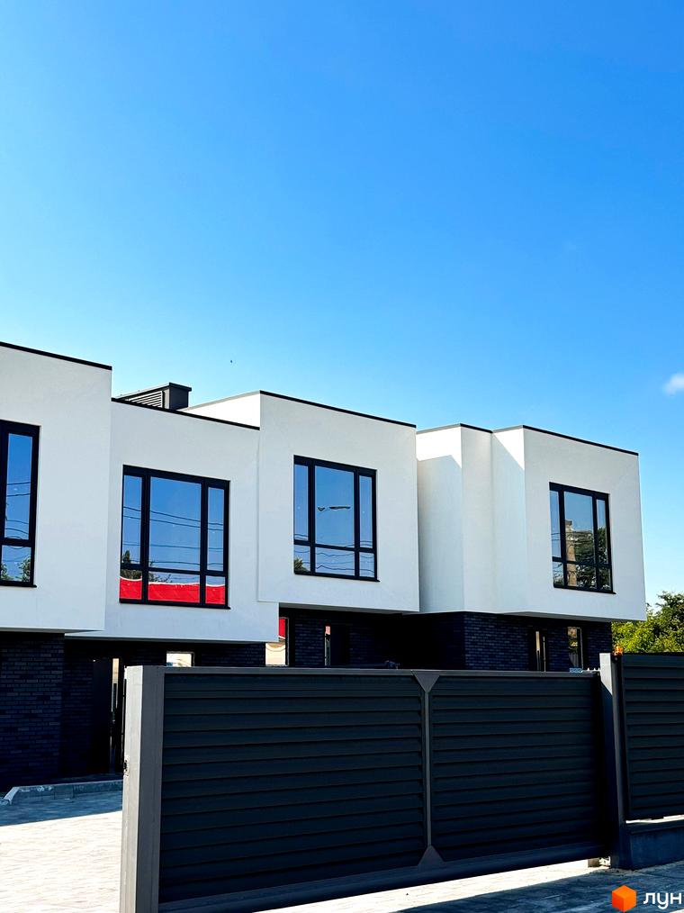 Сучасний житловий комплекс на вул. Троянівська, 21а, з білими фасадами, великими вікнами та темним парканом.